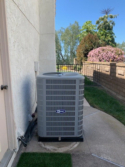AC condenser in a residential side yard, the kind of unit Left Coast Air services and maintains