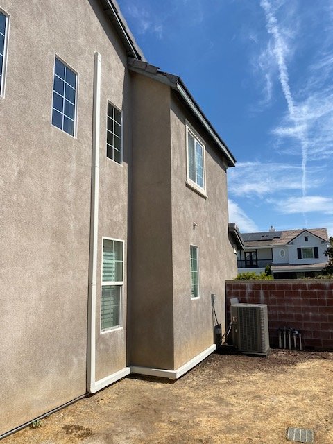 Carrier air conditioning condenser installed by Left Coast Air beside a two-story stucco home