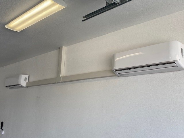 Two indoor ductless mini-split heads mounted in a shop or garage